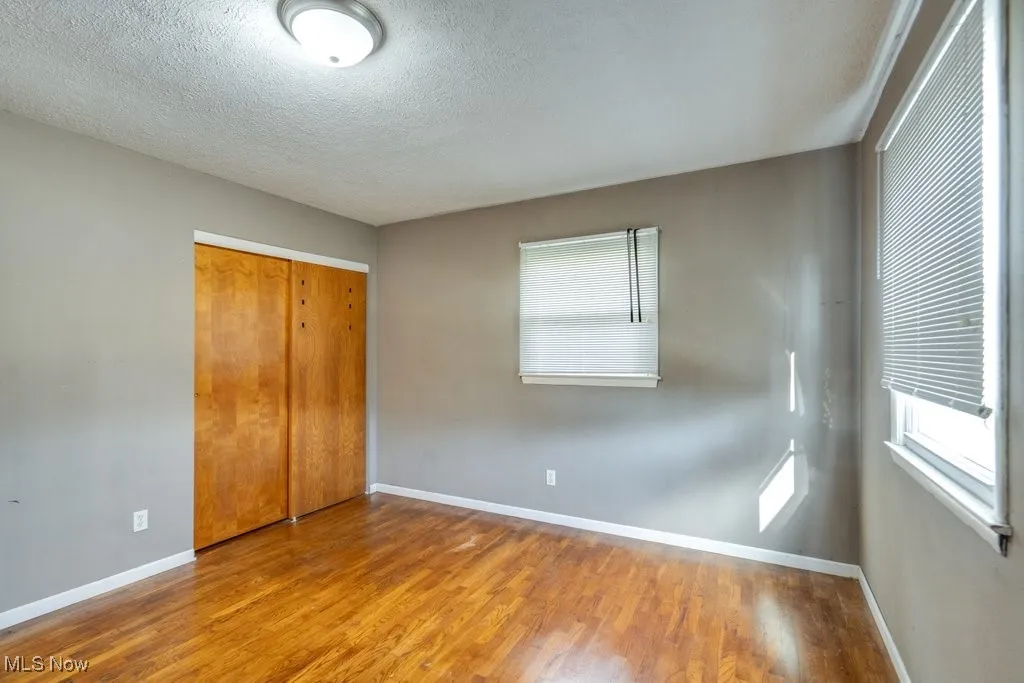 Unfurnished bedroom featuring wood finished floors, a textured ceiling, and a closet