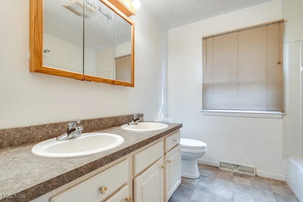 Full bath with double vanity and baseboards
