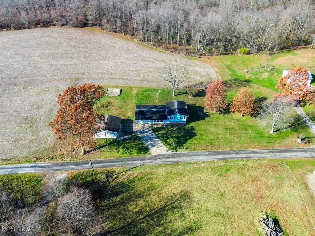 Aerial view of property and surrounding area with a forest