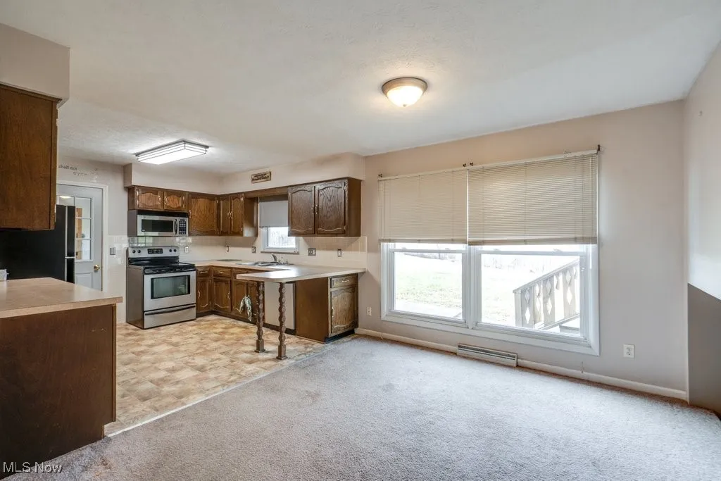 Kitchen with stainless steel appliances, light countertops, and light colored carpet