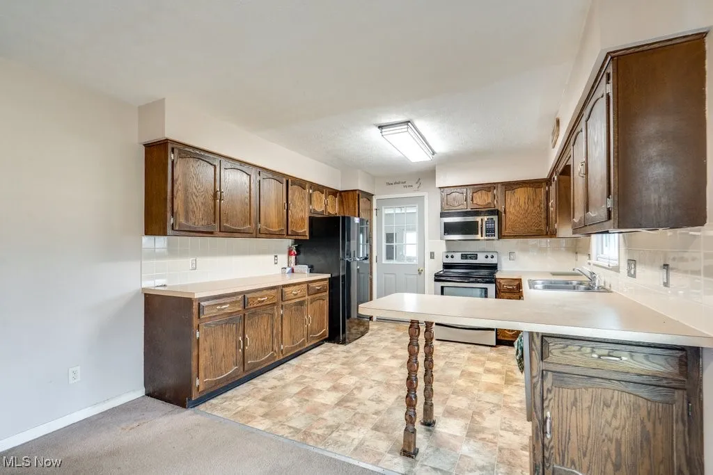 Kitchen featuring tasteful backsplash, stainless steel appliances, and light countertops