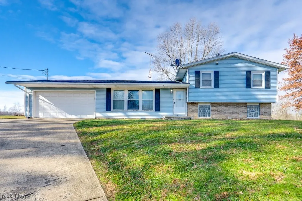 Tri-level home featuring brick siding, an attached garage, concrete driveway, and a front yard