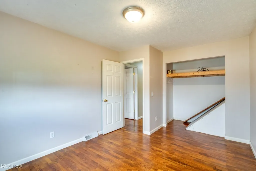 Unfurnished bedroom with a closet, wood finished floors, and a textured ceiling