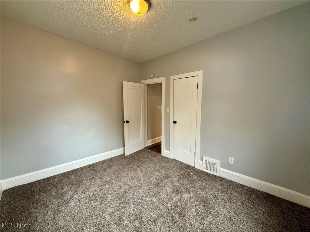Empty room with a textured ceiling and carpet flooring