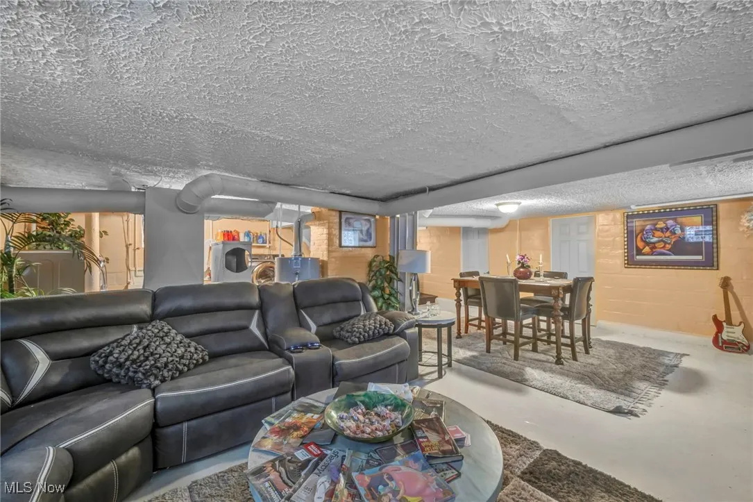 Living room with finished concrete floors, a textured ceiling, and concrete block wall