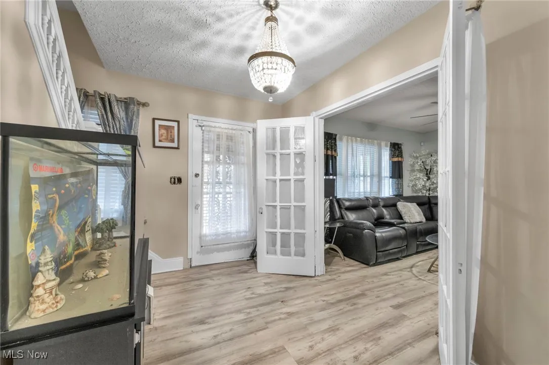 Doorway with wood finished floors, a textured ceiling, and a chandelier