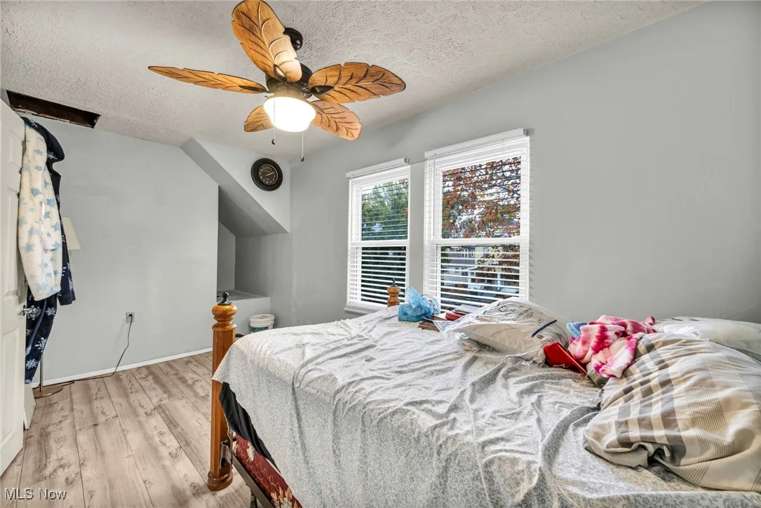 Bedroom featuring a textured ceiling, light wood finished floors, and ceiling fan