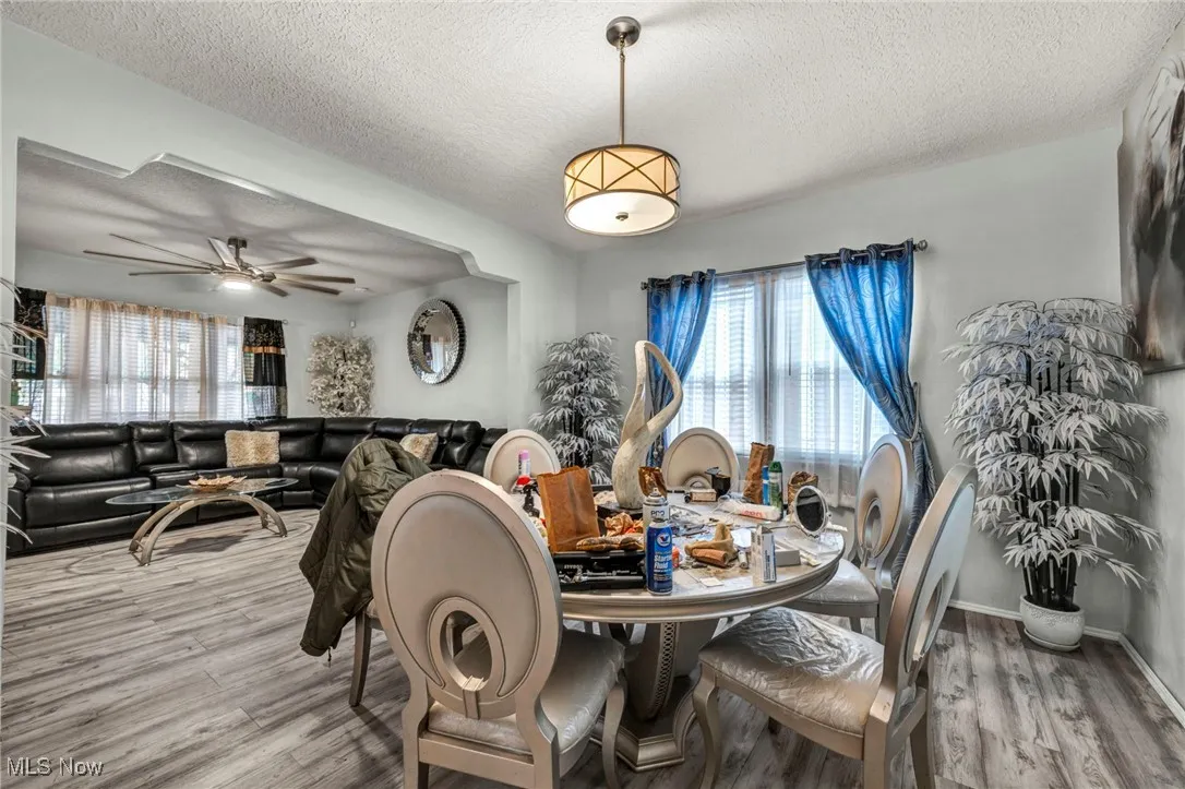 Dining room featuring a textured ceiling, light wood-style floors, and a ceiling fan