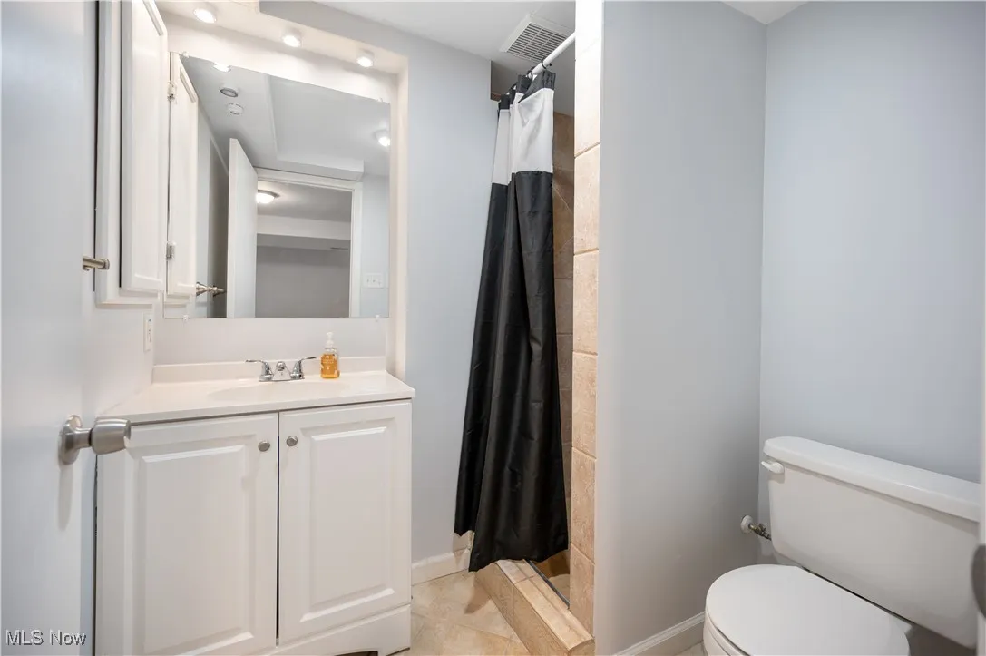 Full bathroom with a shower stall, vanity, and light tile patterned floors