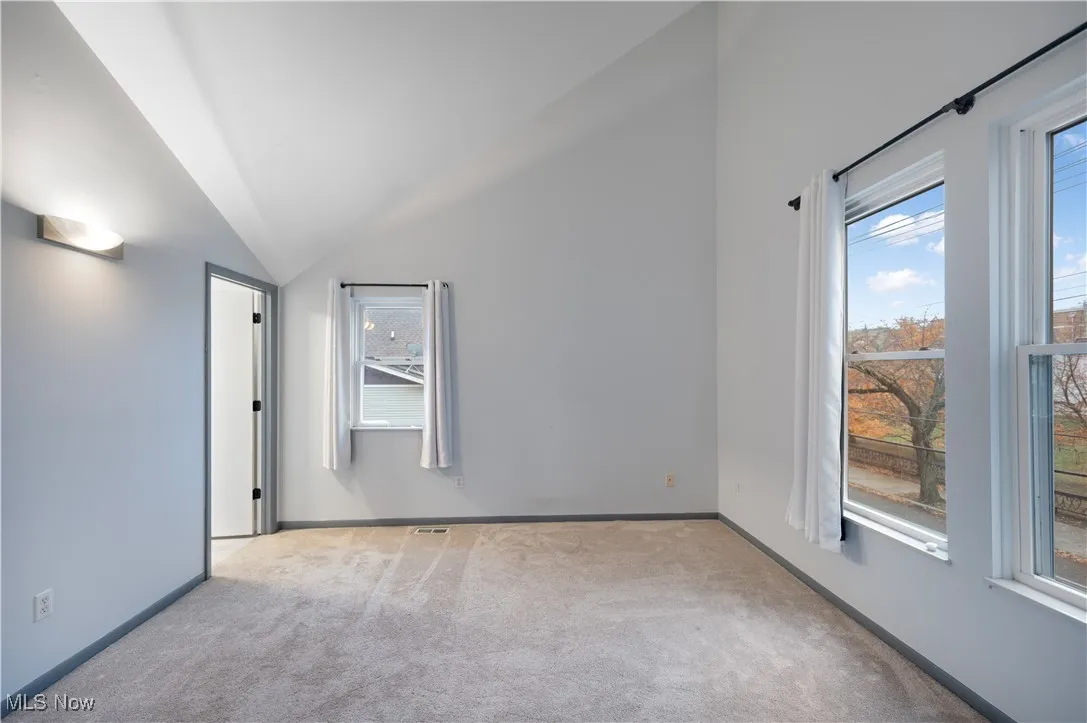 Unfurnished bedroom featuring lofted ceiling and carpet floors