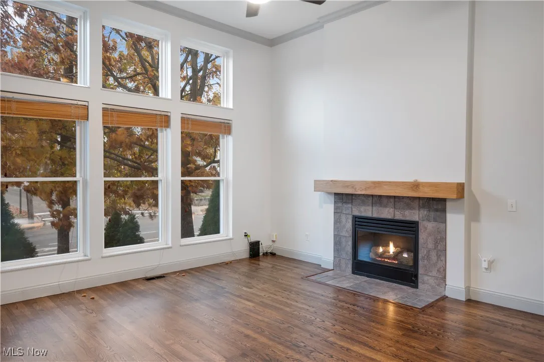 Unfurnished living room with ornamental molding, a fireplace, wood finished floors, and ceiling fan