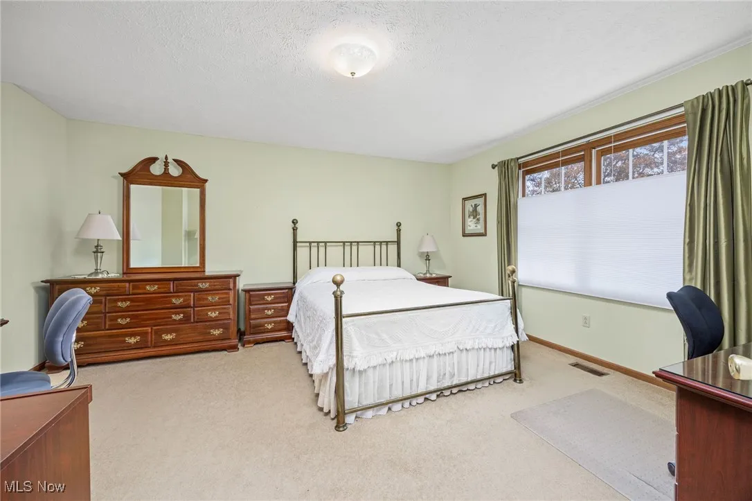Bedroom with a textured ceiling, carpet flooring, and an office area