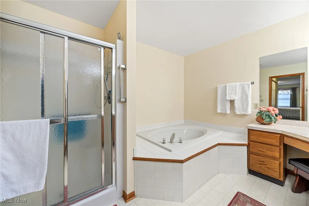 Full bath featuring a bath, light tile patterned floors, and a stall shower