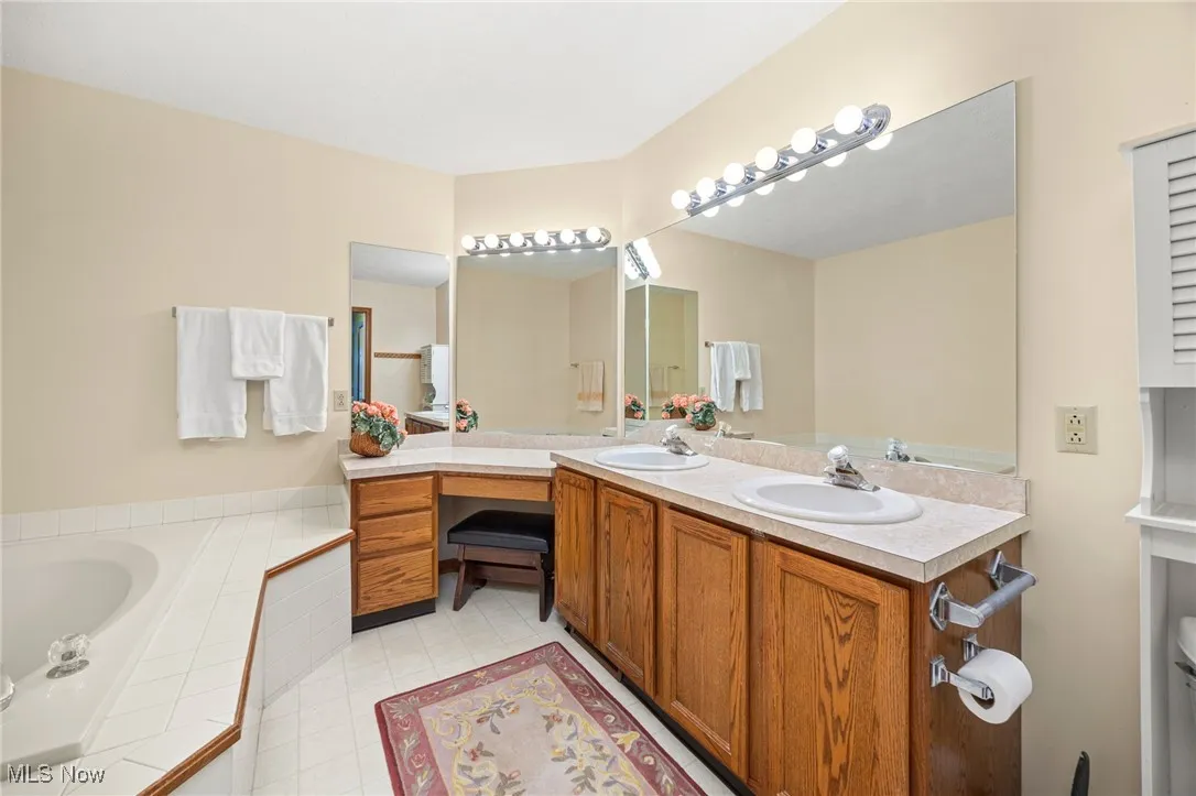 Full bath featuring double vanity, a bath, and light tile patterned floors