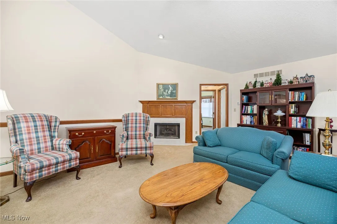 Carpeted living room featuring a premium fireplace and vaulted ceiling