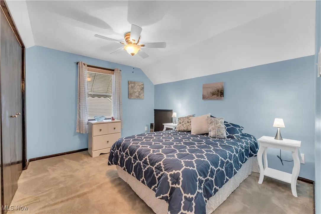 Carpeted bedroom with lofted ceiling, a closet, and a ceiling fan