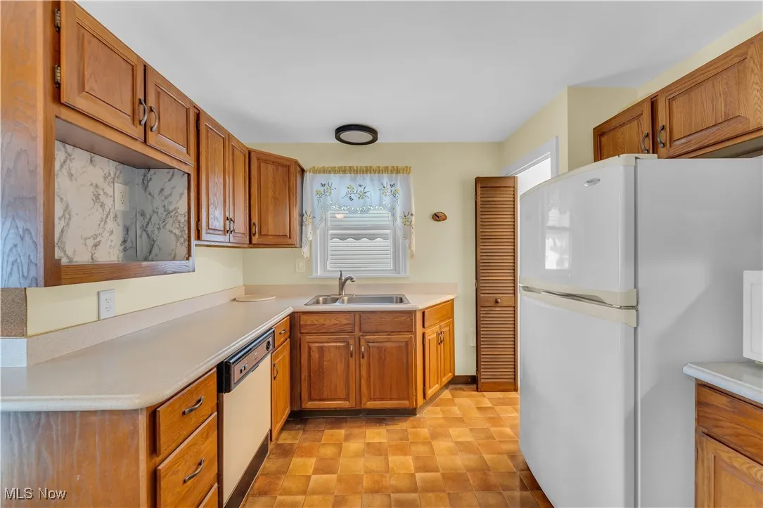 Kitchen featuring white appliances, brown cabinets, and light countertops
