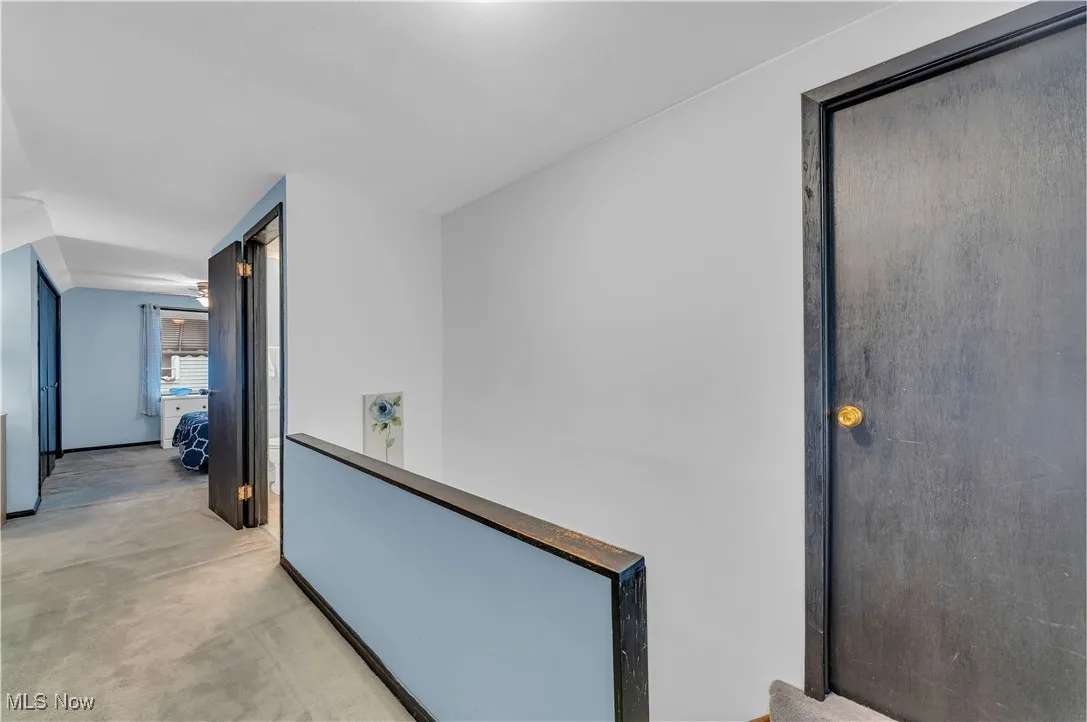 Hall with an upstairs landing and light colored carpet