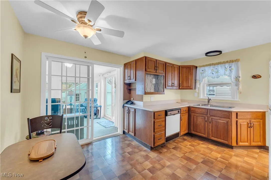 Kitchen with brown cabinetry, light countertops, plenty of natural light, and ceiling fan