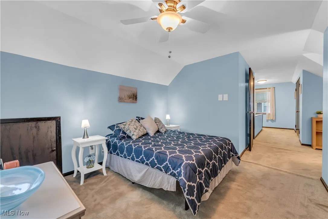 Bedroom featuring light colored carpet, vaulted ceiling, and ceiling fan