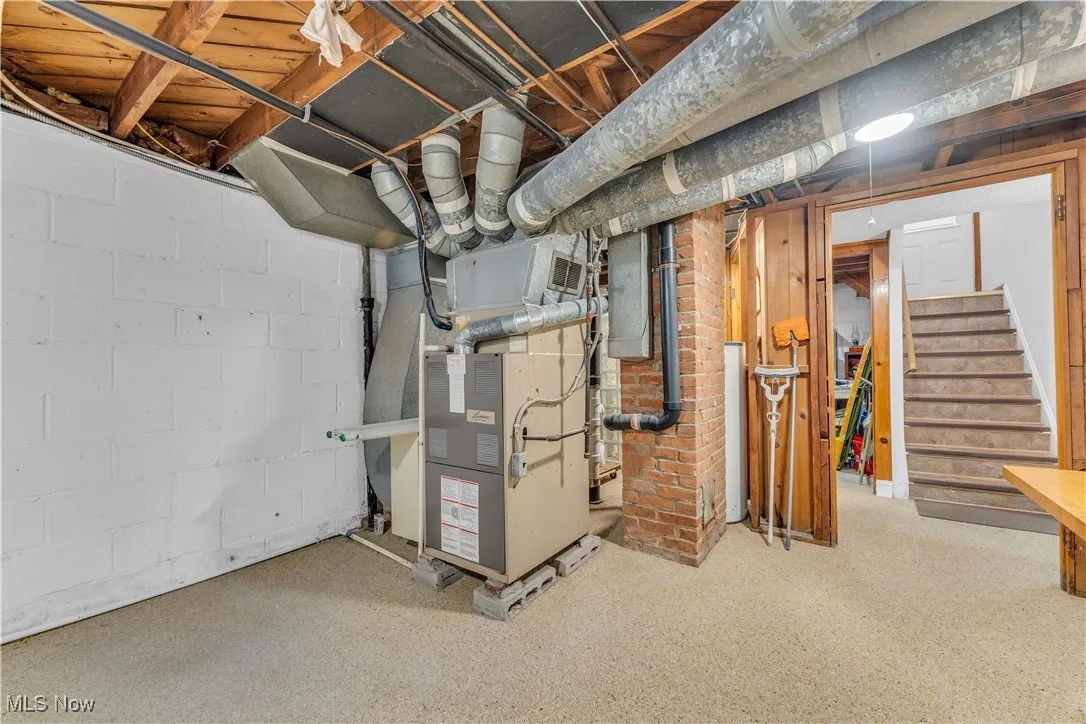 Unfinished below grade area with stairs and heating unit