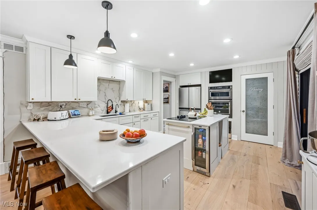 Kitchen breakfast bar with quartz counters and pendant lighting overlooking the kitchen with built in range and stainless steel appliances