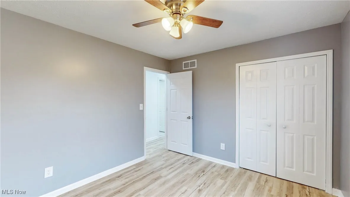 Unfurnished bedroom featuring light wood-type flooring, a closet, and ceiling fan