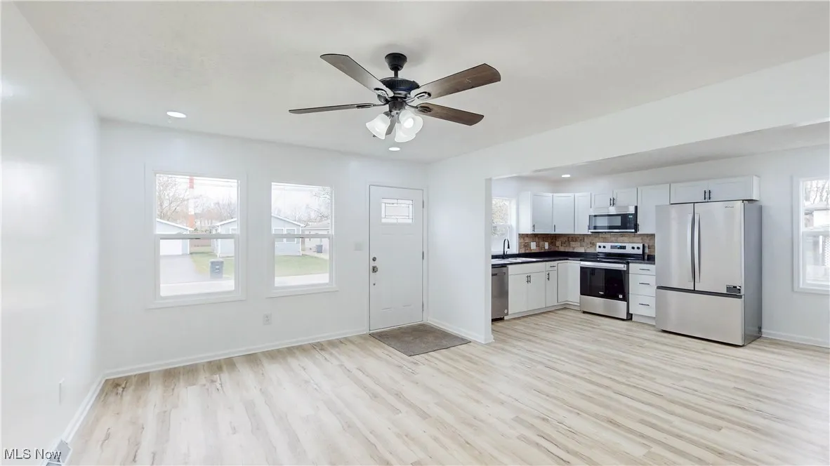 Kitchen with stainless steel appliances, white cabinetry, dark countertops, recessed lighting, and ceiling fan