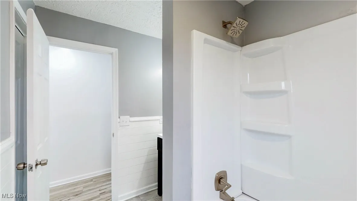 Bathroom featuring vanity, a textured ceiling, a shower, and light wood-style floors