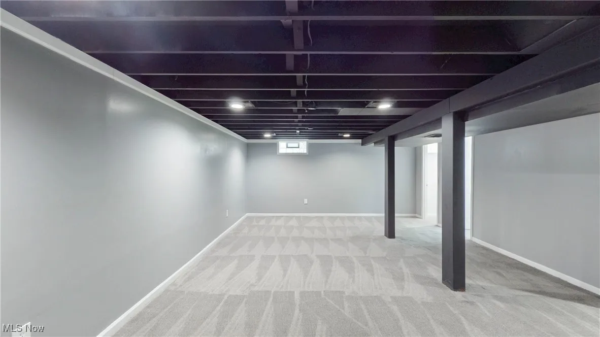 Basement with light colored carpet and baseboards