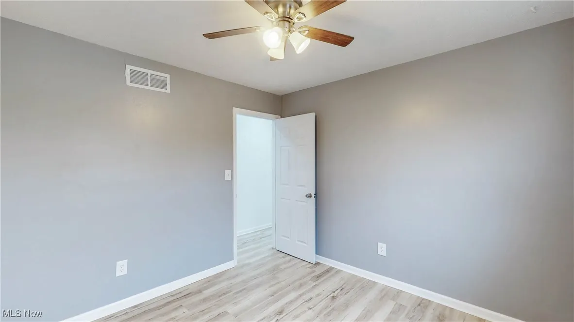 Empty room with light wood finished floors and a ceiling fan