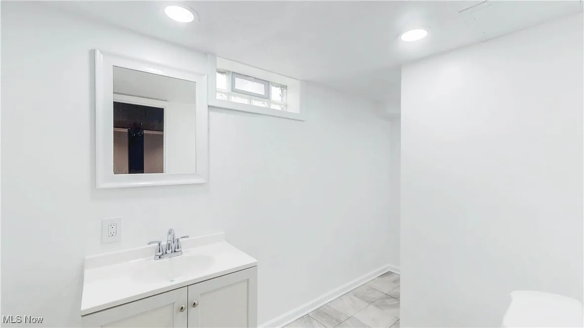 Bathroom featuring vanity, light marble finish floors, and recessed lighting