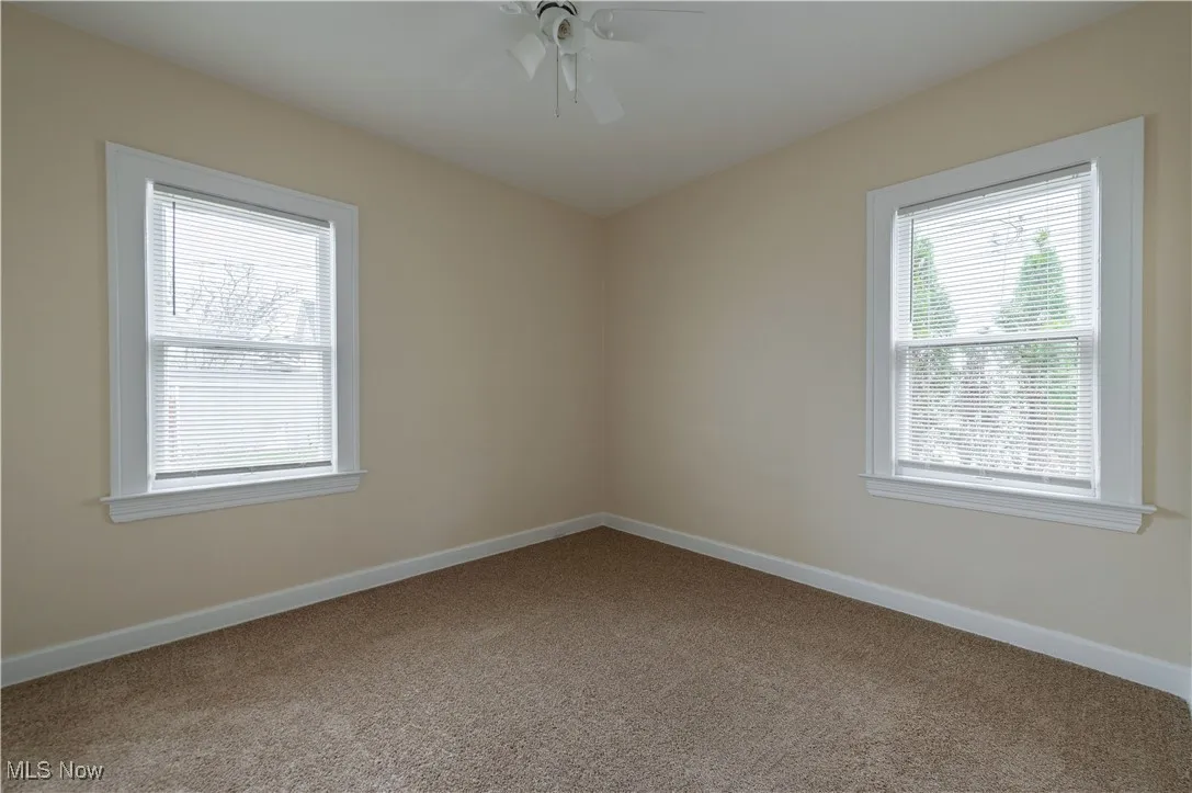Carpeted spare room featuring baseboards and a ceiling fan