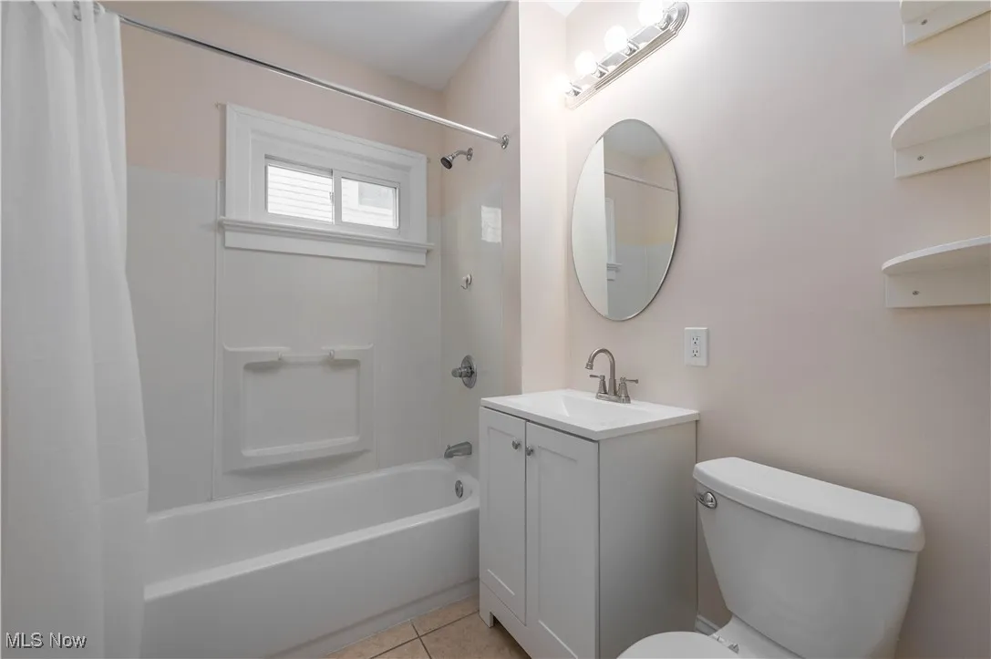 Bathroom featuring shower / tub combo, vanity, and light tile patterned floors