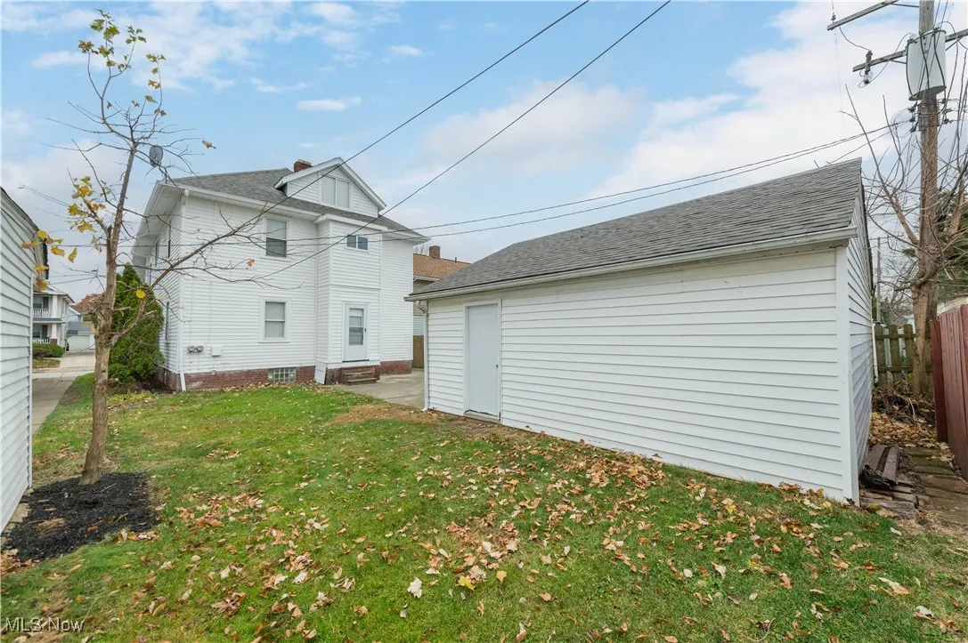 Rear view of house featuring an outbuilding, a patio, and a shingled roof