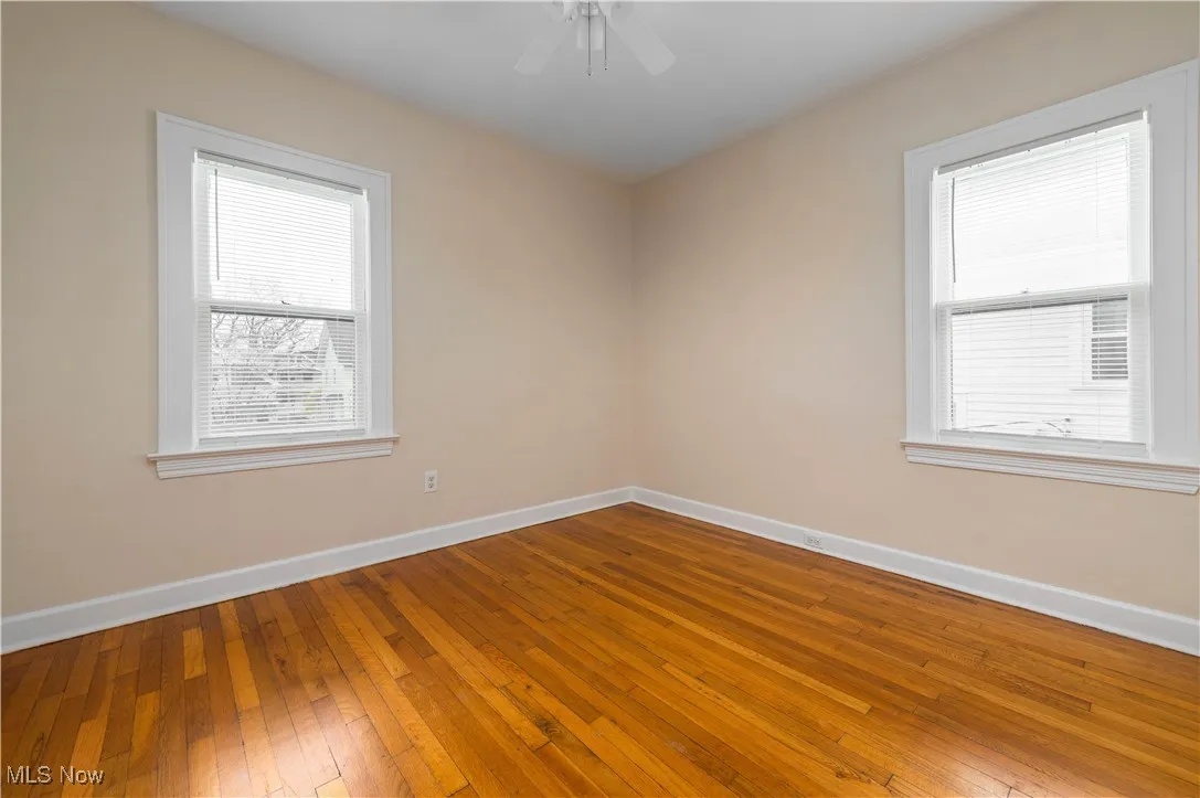 Spare room featuring wood-type flooring, plenty of natural light, and ceiling fan
