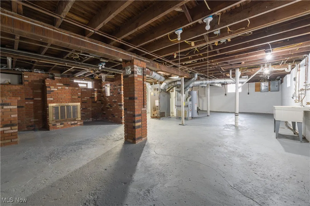 Basement with heating unit, water heater, and electric panel
