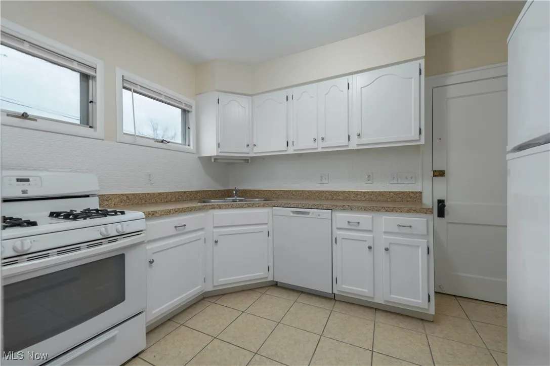 Kitchen featuring white appliances, white cabinetry, light countertops, and light tile patterned floors