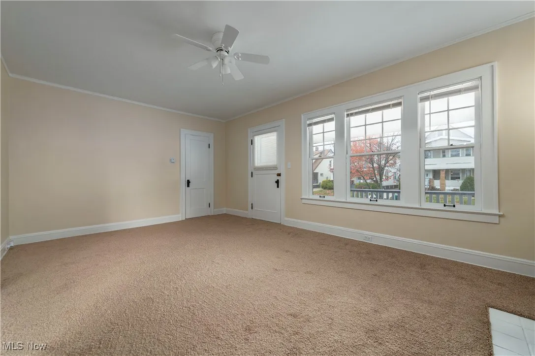 Carpeted empty room with crown molding and ceiling fan