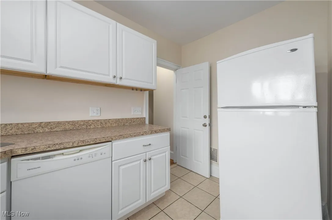 Kitchen featuring white appliances, white cabinetry, light countertops, and light tile patterned floors
