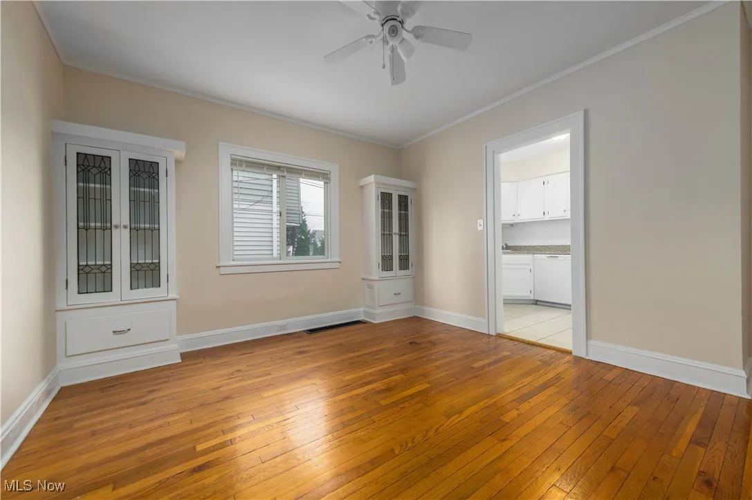 Spare room with light wood-style floors, crown molding, and ceiling fan