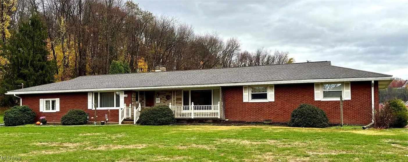 Single story home featuring a porch, a front lawn, and brick siding