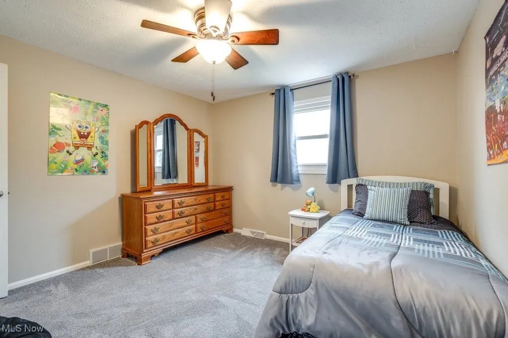 Bedroom with carpet, a ceiling fan, and a textured ceiling