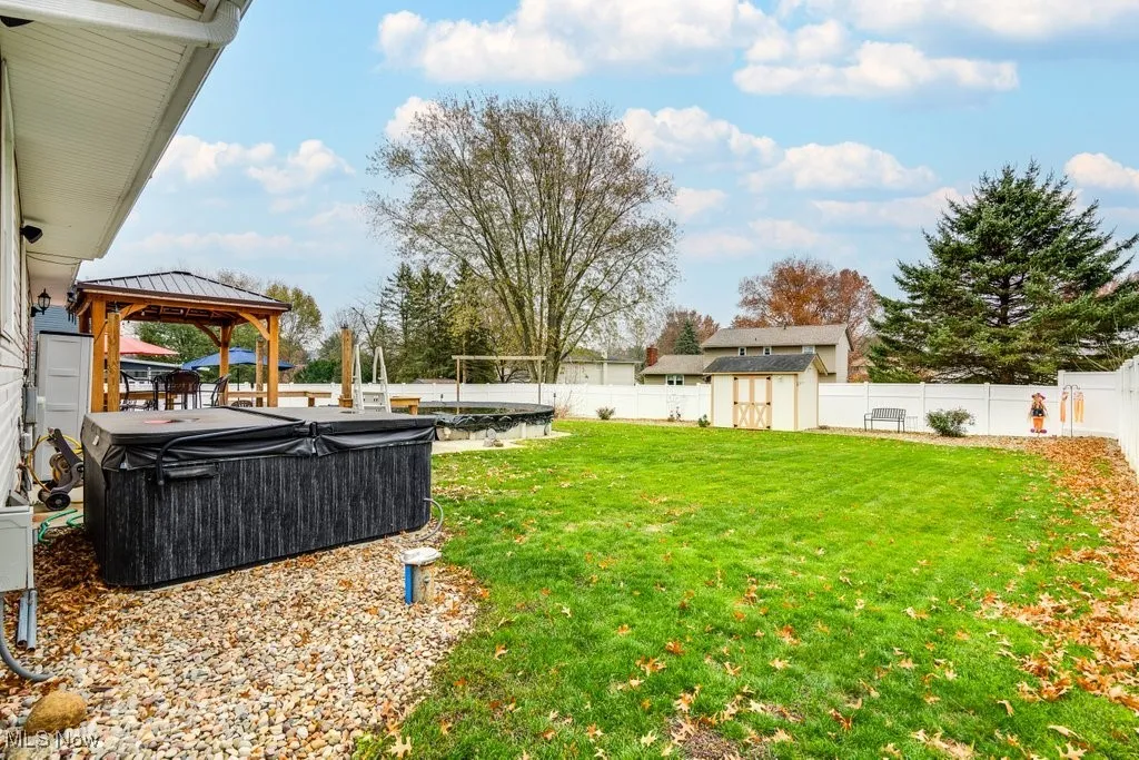 Fenced backyard with a gazebo, a storage unit, and a swimming pool