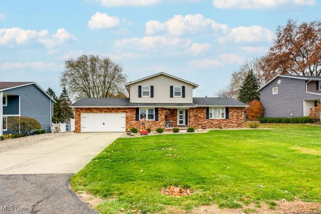 Traditional home featuring driveway, a front lawn, an attached garage, and brick siding