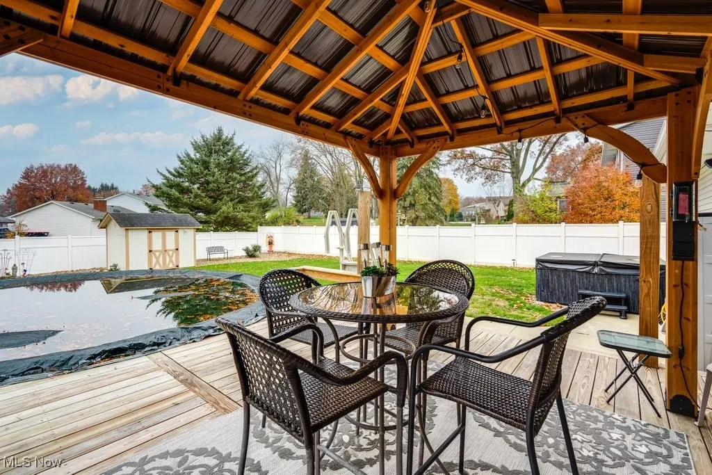 Fenced backyard featuring outdoor dining space, a shed, a hot tub, a pool, and a deck