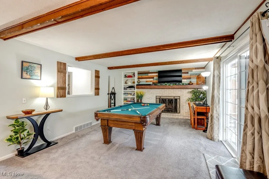 Recreation room with beamed ceiling, a fireplace, billiards table, and carpet