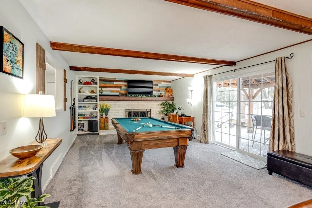 Rec room with billiards table, carpet floors, beam ceiling, and a fireplace