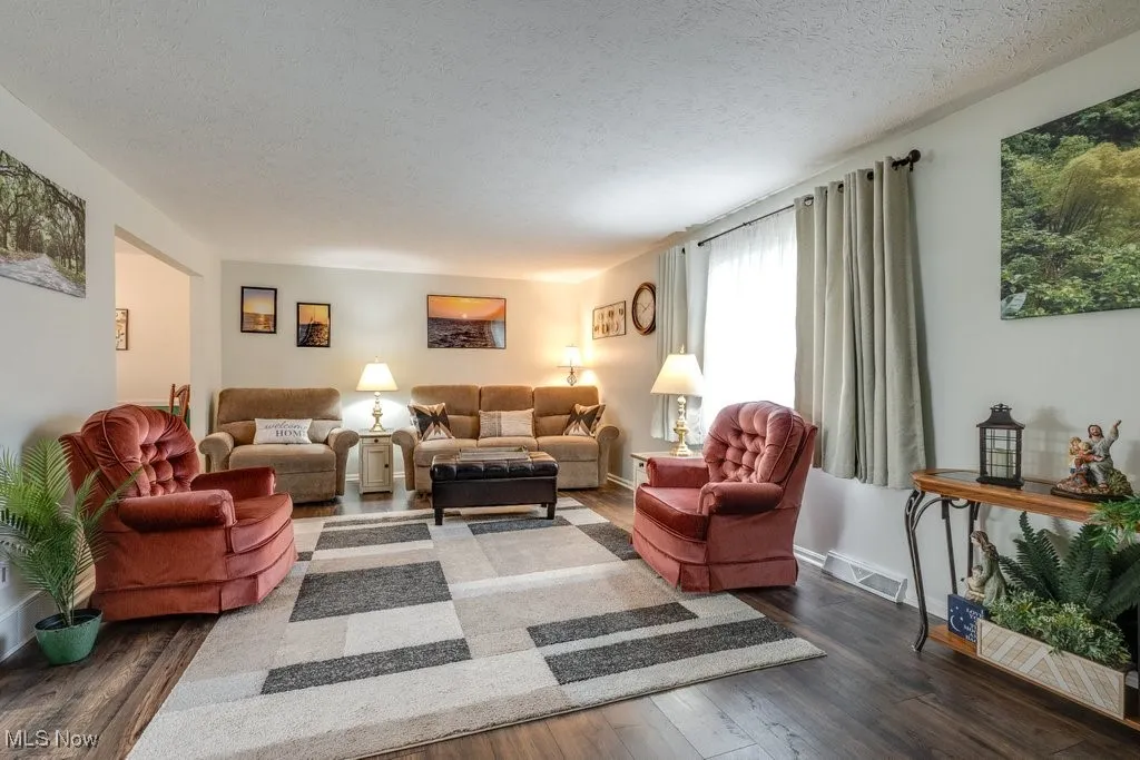 Living room with a textured ceiling and dark wood finished floors