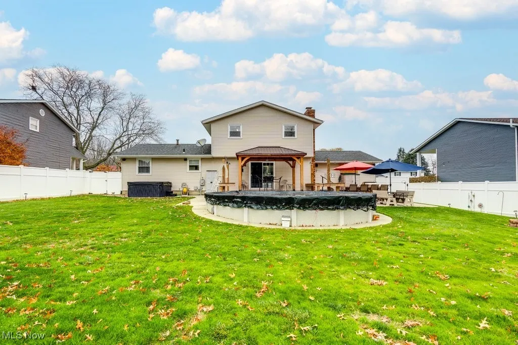 Back of property featuring a gazebo, a fenced backyard, a chimney, and a patio area